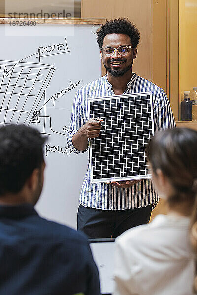 Geschäftsmann hält im Büro eine Präsentation und hält ein Solarpanel in der Hand