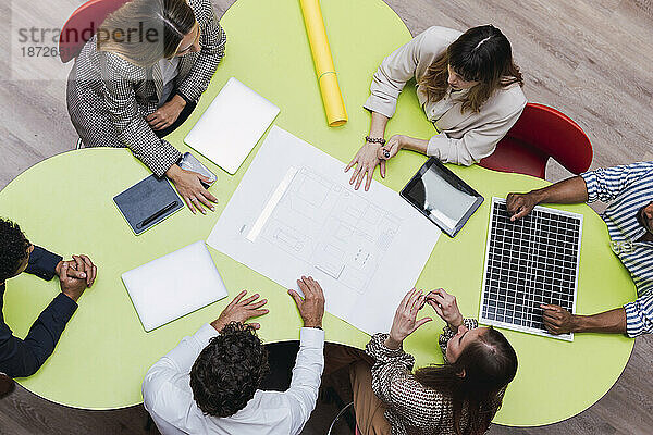 Blick aus der Vogelperspektive auf Geschäftskollegen bei einem Meeting mit Plan  drahtlosen Geräten und Solarpanel auf dem Tisch