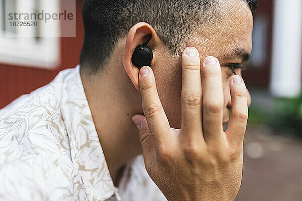 Junger Mann passt In-Ear-Kopfhörer an