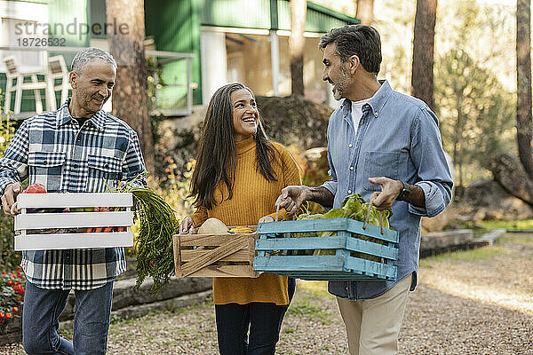 Freunde tragen Kisten mit frisch geerntetem Bio-Gemüse auf dem Bauernhof