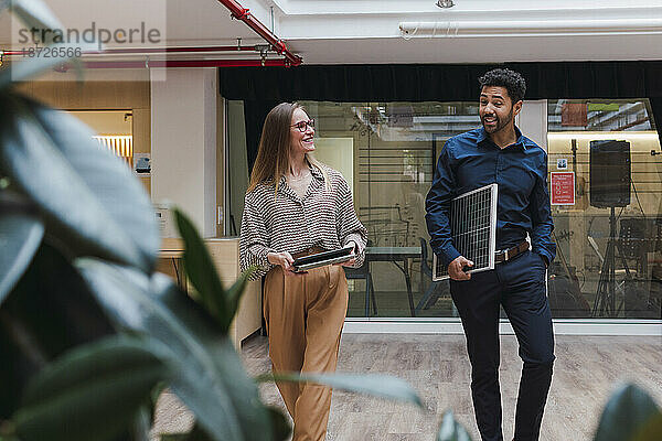 Geschäftsmann mit Solarpanel und Geschäftsfrau mit digitalem Tablet gehen im Büro