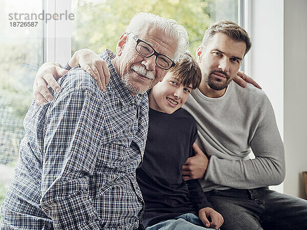 Grandfather  father and son sitting by the window at home