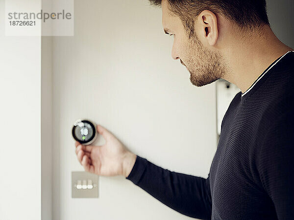 Mann passt die intelligente Thermostatsteuerung an der Wand zu Hause an