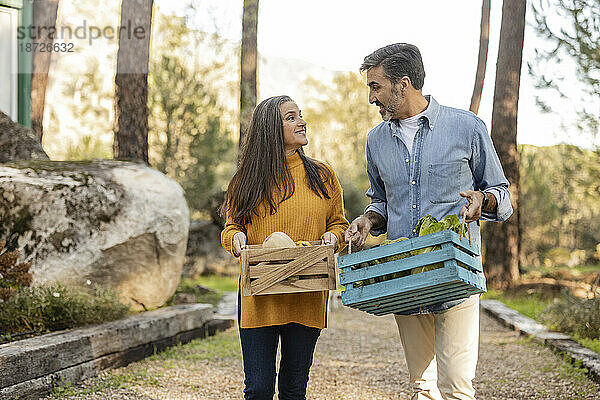 Mann und Frau tragen Kisten mit frisch geerntetem Bio-Gemüse