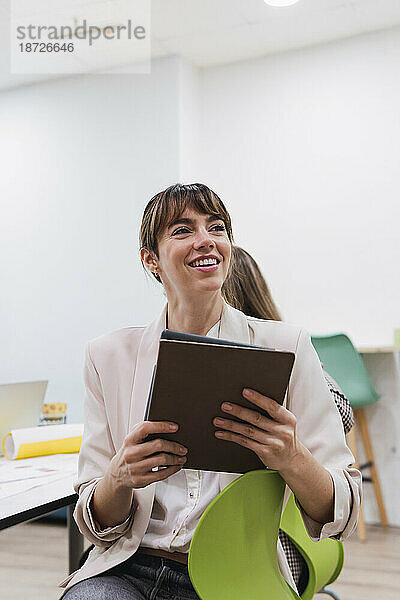 Lächelnde Geschäftsfrau hält Tablet im Bürokonferenzraum