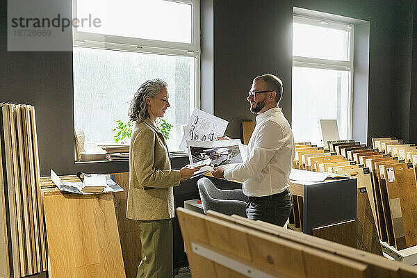 Zwei Kollegen halten den Ausdruck eines Hauses und den Bauplan im Architekturbüro in der Hand