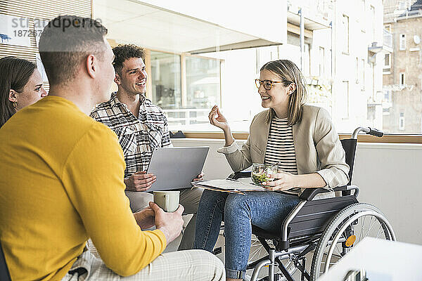 Junge Geschäftsleute treffen sich im Büro mit einer Frau im Rollstuhl