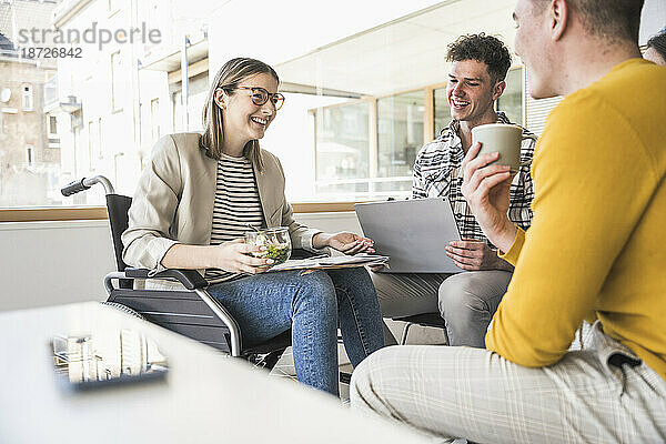 Junge Geschäftsleute treffen sich im Büro mit einer Frau im Rollstuhl