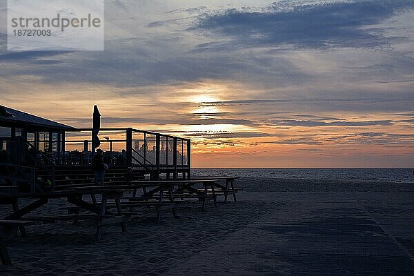 Silhouette der Außenterrasse des Strandpavillons 'Paal 17' mit Meeresszene bei Sonnenuntergang im Hintergrund auf der Insel Texel im Norden der Niederlande