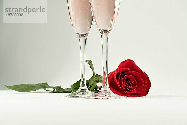 Zwei Gläser Champagner und eine Rose auf einem weißen Hintergrund und Kopierraum Valentinstagssymbol