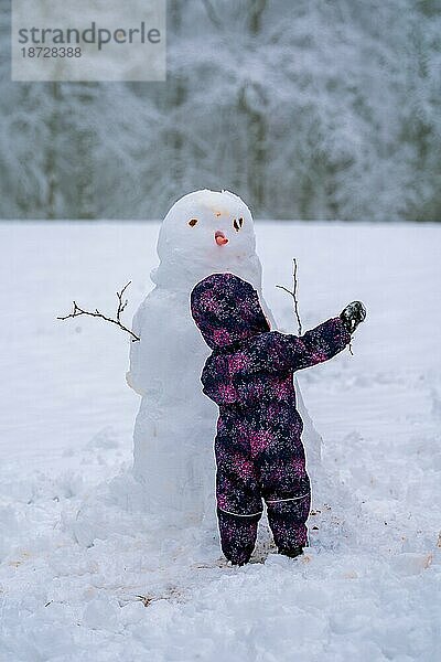 Ein Kleinkind spielt mit einem Schneemann