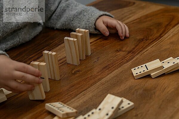 Kinderhände in grauem Pullover spielen Domino mit unscharfem Fokus