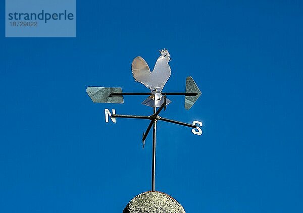 Wetterhahn in Form eines Hahns am blauen Himmel