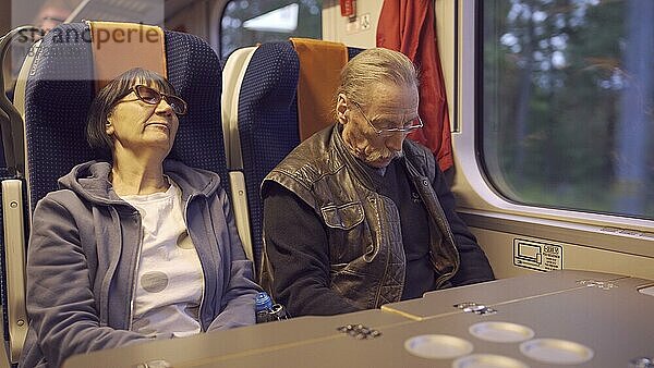 Ein älteres Ehepaar fährt frühmorgens mit dem Zug und schläft