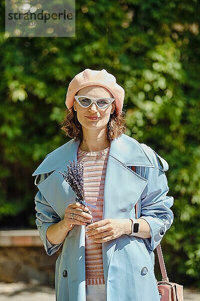 Outdoor Portrait einer fröhlichen  modischen Frau mit Lavendel in den Händen