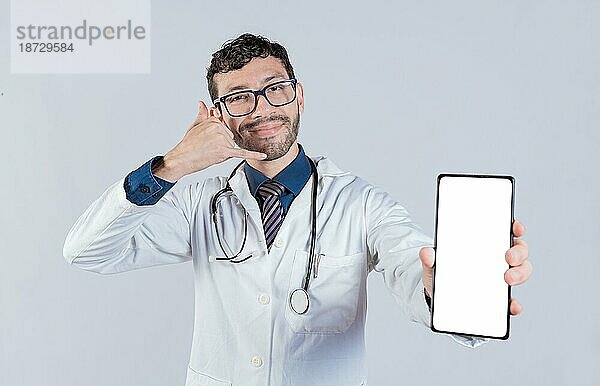 Handsome Arzt zeigt Handybildschirm gestikulieren rufen Sie mich an. Glücklicher Arzt zeigt weißen Bildschirm des Handys