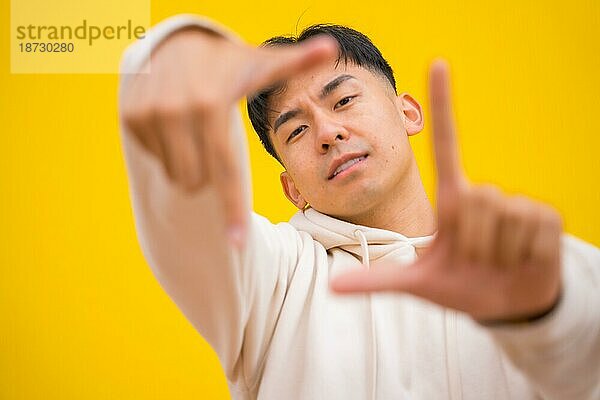 Porträt eines südkoreanischen Mannes in einfacher Kleidung auf gelbem Hintergrund  der lächelt und Spaß hat