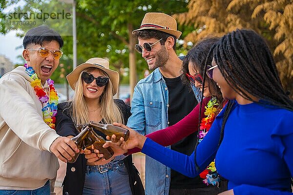 Gruppe multiethnischer Freunde auf einer Party in einem Park  die sich amüsieren  Verschiedene junge Leute stoßen mit Glasflaschen Bier auf einer Sommerparty an  Jugendkonzept