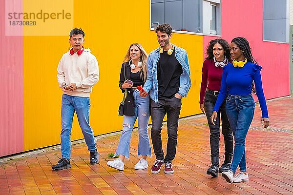 Gruppe multiethnischer Freunde  die auf dem Universitätscampus spazieren gehen und Spaß haben  junges Millennial-Handy-Technologiekonzept