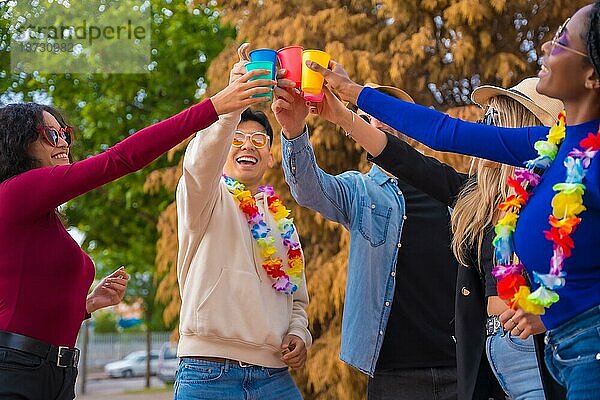 Eine Gruppe multiethnischer Freunde feiert in einem Park  Verschiedene junge Leute stoßen mit Biergläsern auf einer Sommerparty an  Happy Hour  Mittagspause und Jugendkonzept