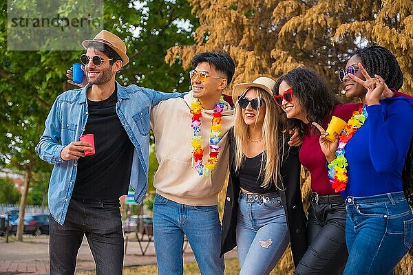 Gruppenbild von multiethnischen Freunden  die eine Party im Park feiern  Verschiedene junge Leute mit Biergläsern auf einer Sommerparty  Happy Hour  Mittagspause und Jugendkonzept