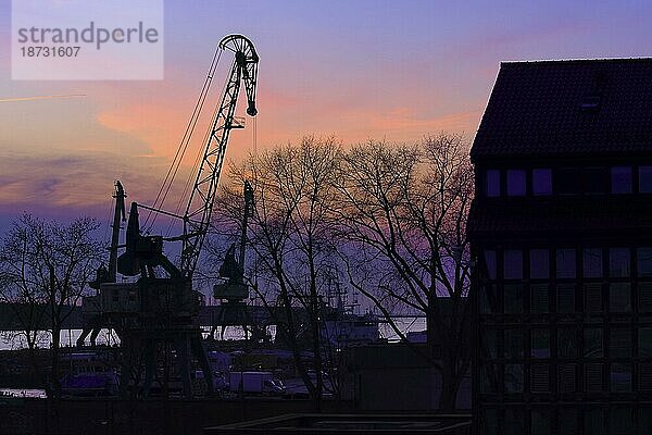 Silhouetten von Hafenkran  Bäume und Gebäude in schönen bunten Sonnenuntergang im Hafen in Klaipeda  Litauen  Europa