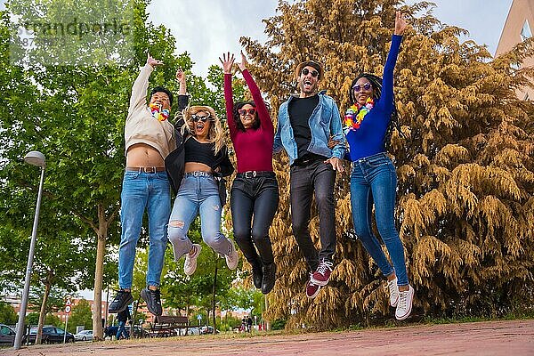 Eine Gruppe multiethnischer Freunde feiert eine Party in einem Park  Verschiedene junge Leute springen vor Freude in einem Sommerparty-Portrait  Happy Hour  Mittagspause und Jugendkonzept