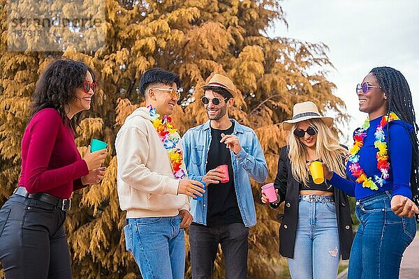 Eine Gruppe multiethnischer Freunde tanzt auf einer Party im Park  Verschiedene junge Leute stoßen mit Biergläsern auf einer Sommerparty an  Happy Hour  Mittagspause und Jugendkonzept