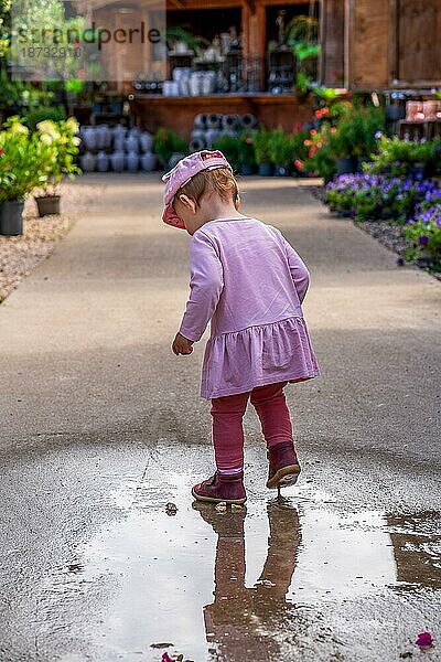 Ein kleines Kind spielt in einer Regenpfütze