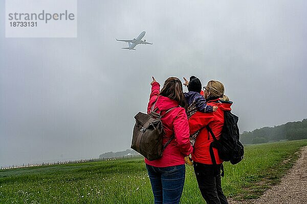 Zwei Frauen mit einem Kind im Arm beobachten Flugzeuge