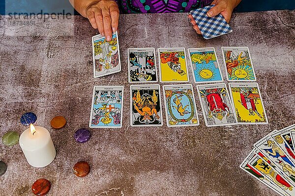 Frau liest Tarotkarten mit Kerzen und Chakra Steinen
