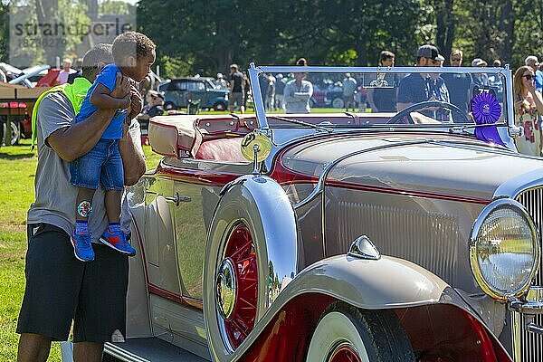 Ein Mann hält einen Jungen hoch  um einen Studebaker Roadster von 1931 auf der Eyes on Design Auto Show zu sehen. Die diesjährige Ausstellung zeigte vor allem Marken  die es nicht mehr gibt  Grosse Pointe Shores  Michigan