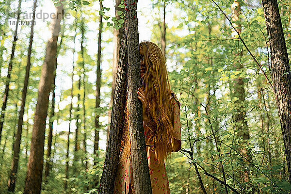 Junge Frau berührt Baum im Wald