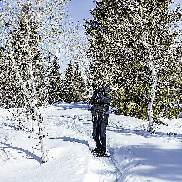 USA  Idaho  Sun Valley  Seniorin mit Schneeschuhen beim Wandern im verschneiten Wald
