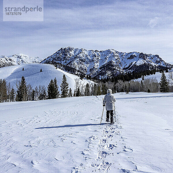 USA  Idaho  Sun Valley  Seniorin mit Schneeschuhen beim Wandern in den Bergen