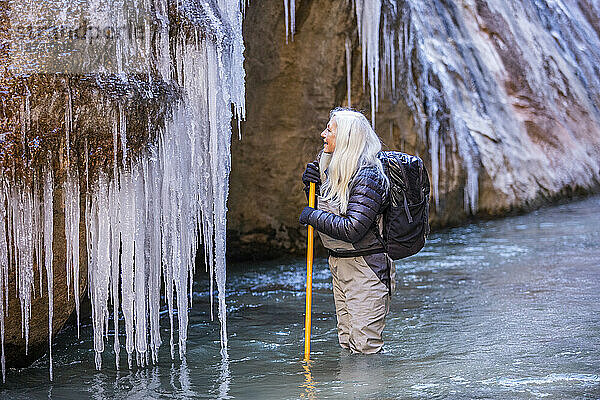 USA  Utah  Springdale  Zion-Nationalpark  Seniorin blickt beim Wandern in den Bergen auf Eiszapfen