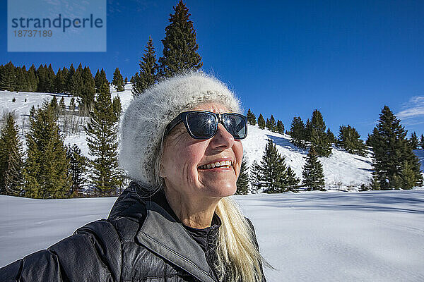 Lächelnde ältere Frau entspannt sich in den Bergen