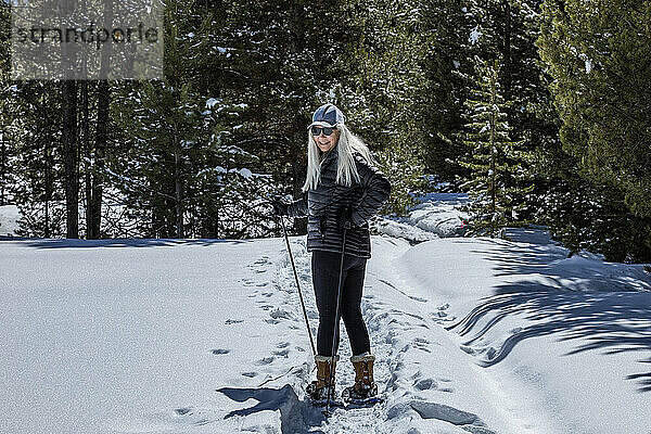 USA  Idaho  Sun Valley  Seniorin mit Schneeschuhen beim Wandern im verschneiten Wald