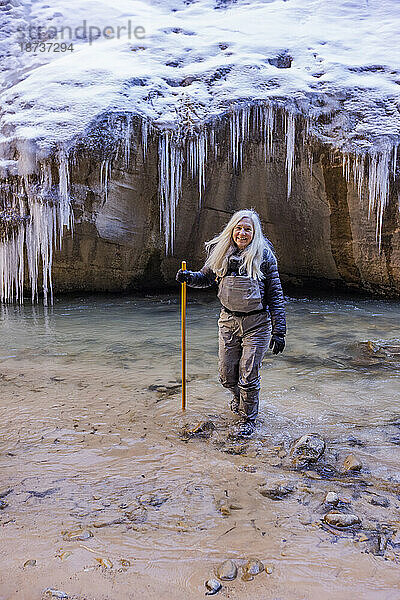 USA  Utah  Springdale  Zion-Nationalpark  Seniorin überquert den Fluss beim Wandern in den Bergen