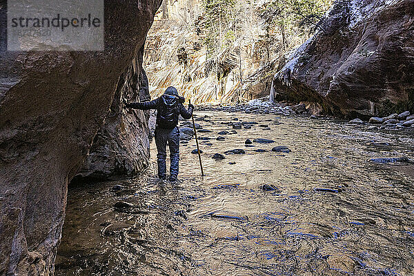 USA  Utah  Springdale  Zion-Nationalpark  Seniorin überquert den Fluss beim Wandern in den Bergen