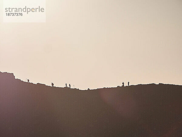 Neuseeland  Waikato  Tongariro-Nationalpark  Silhouetten von Wanderern auf einem Bergrücken bei Sonnenuntergang