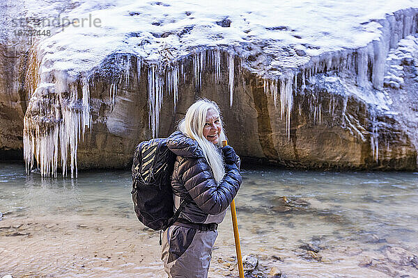 USA  Utah  Springdale  Zion-Nationalpark  Seniorin überquert den Fluss beim Wandern in den Bergen