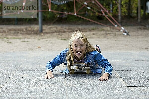 Mädchen (10) liegt auf Skateboard  Kiel  Schleswig-Holstein  Deutschland  Europa