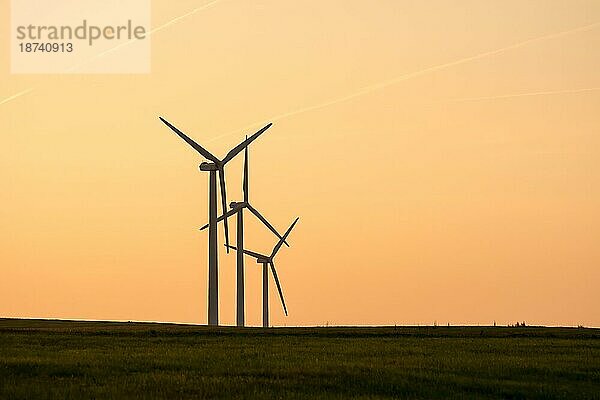 Alternative Energie mit Windkraft drei Windradsilhouetten im Sonnenuntergang