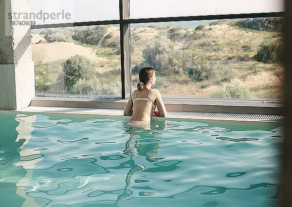 Junges Mädchen schwimmt im Pool eines Luxus Spa Center durch die großen Fenster mit Blick. Spa  Urlaub Konzept