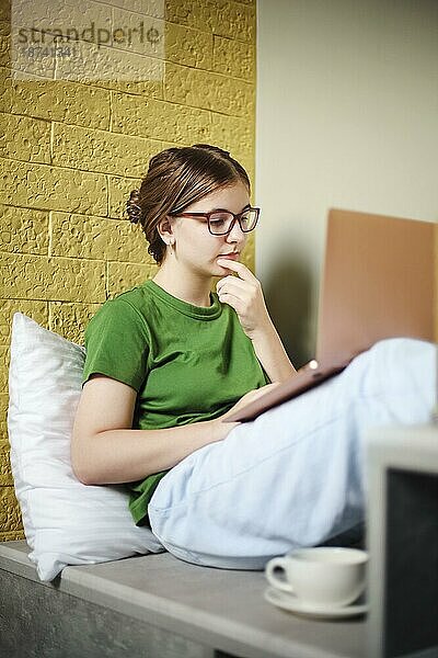 Weiblicher Teenager mit Netbook beim Entspannen auf der Treppe. Heimunterricht und Lernkonzept