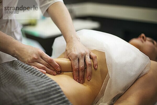 Teilansicht eines Masseurs bei der Bauchmassage einer Frau auf dem Massagetisch