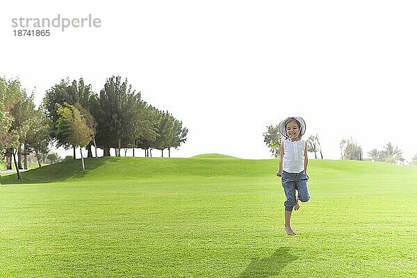 Fröhlich niedlichen Kind im Moment der Sprung über grüne Wiese im Sommer auf sonnigen Tag