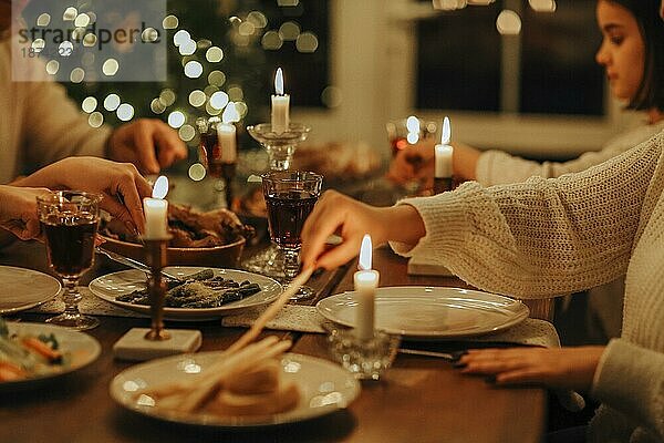 Glückliche Großfamilie mit vielen Kindern  die Weihnachten oder Silvester zusammen in einem gemütlichen  warmen Haus feiern und sich um einen festlichen Tisch mit köstlichen traditionellen Weihnachtsgerichten versammeln