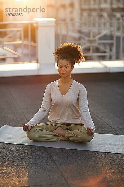 Ausgeschnittenes Foto einer Frau  die im Lotussitz auf einer Matte sitzt und Yoga praktiziert  eine Frau  die die Namaste Geste macht  während sie im Freien meditiert. Meditation und Achtsamkeit Konzept